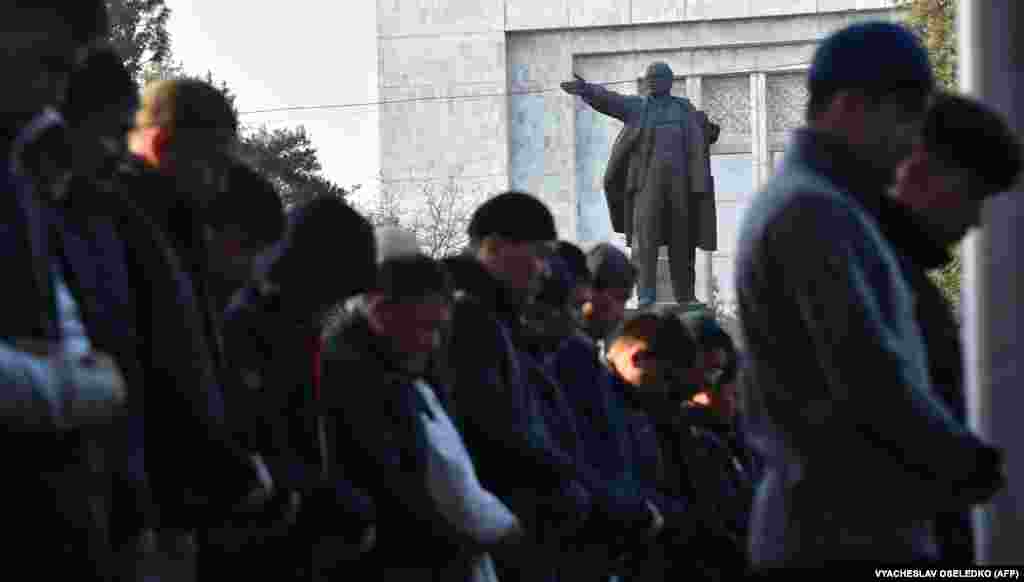 Kyrgyz Muslims attend morning Eid al-Fitr prayers in central Bishkek next to a monument of former Soviet leader Vladimir Lenin.