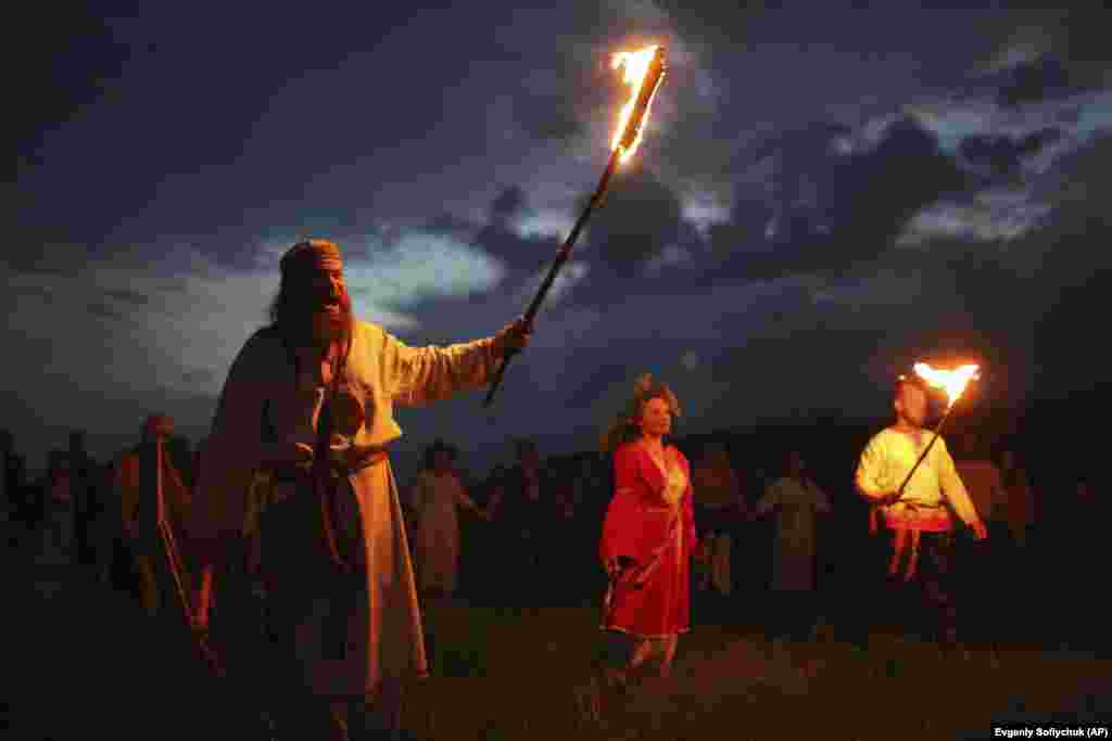 People with torches wearing traditional Russian village-style clothes celebrate the summer solstice near a bonfire in the village of Okunevo, about 200 kilometers northeast of the Siberian city of Omsk.