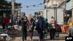 Палестинцы несут вещи, покидая свой дом в поисках более безопасного места после израильского авиаудара в Рафахе на юге сектора Газа, 18 октября 2023 года
