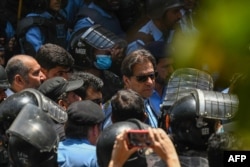Police officers escort Pakistan's former Prime Minister Imran Khan (center) as he arrives at the high court in Islamabad on May 12.