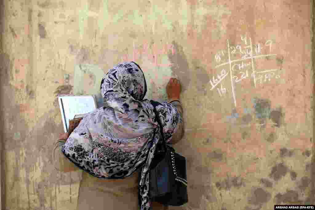 Një punonjëse shëndetësore shkruan në murin e një shtëpie, në të cilën ajo ka vaksinuar një fëmijë gjatë fushatës së vaksinimit kundër poliomielitit&nbsp; derë më derë në Peshavar, Pakistan.