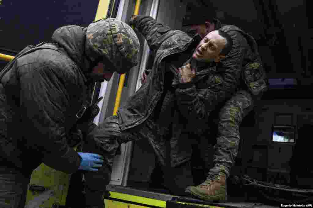 Ukrainian military medics help a wounded comrade out of an ambulance.