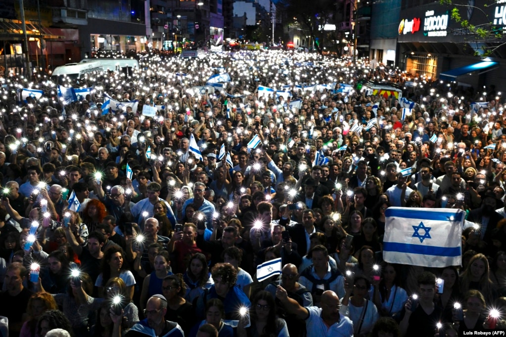 Turma njerëzish duke mbajtur lart telefona mobilë dhe flamuj izraelitë, gjatë një tubimi në Buenos Aires, Argjentinë, më 9 tetor.