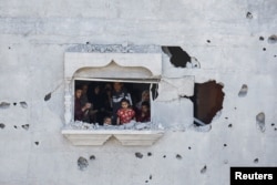 Палестинско семейство гледа през прозорец на засегната от израелски удар сграда в Рафах, 2 април 2024 г. Снимка: Мохамед Салем