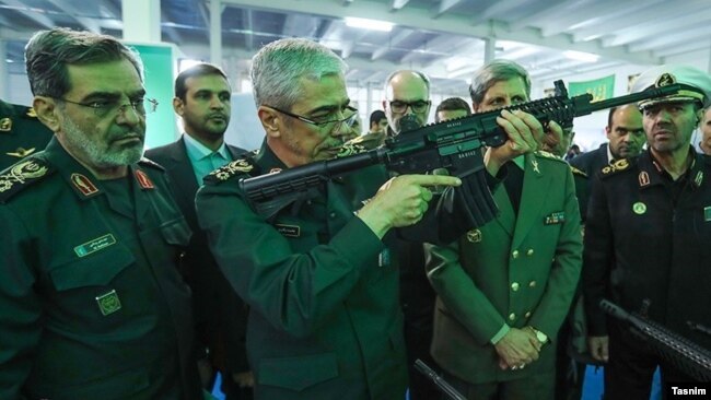 محمد باقری رئیس ستاد کل نیروهای مسلح (نفر وسط) در یک نمایشگاه نظامی اسلحه به دست گرفته است