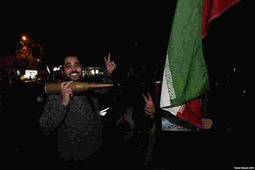 Iranian demonstrators flash the victory sign as they hold an Iranian flag and a model of a bullet during an anti-Israeli gathering at Palestine Square. Israel has neither confirmed nor denied responsibility for the consulate attack.