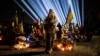 Mama și fiica ei ascultă rugăciunea pentru soldații căzuți la datorie într-un cimitir din Lvov, în vestul Ucrainei, pe 23 februarie
