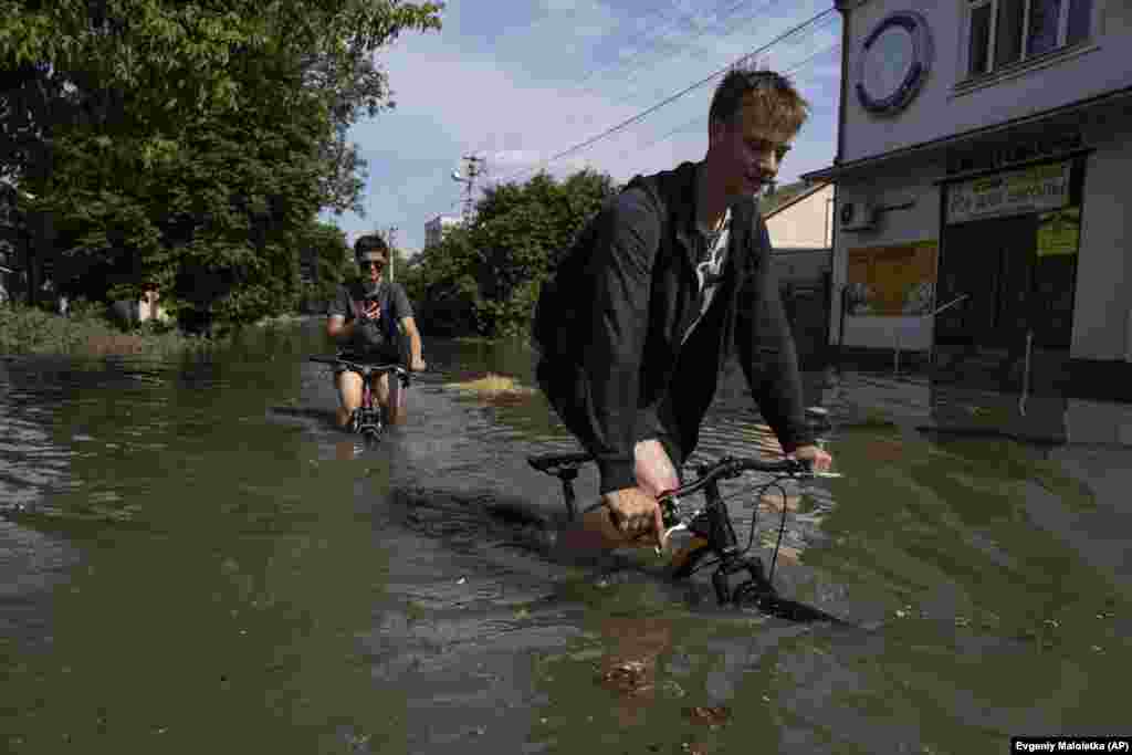 Local residents try to ride their bikes along a flooded road in Kherson. &nbsp;