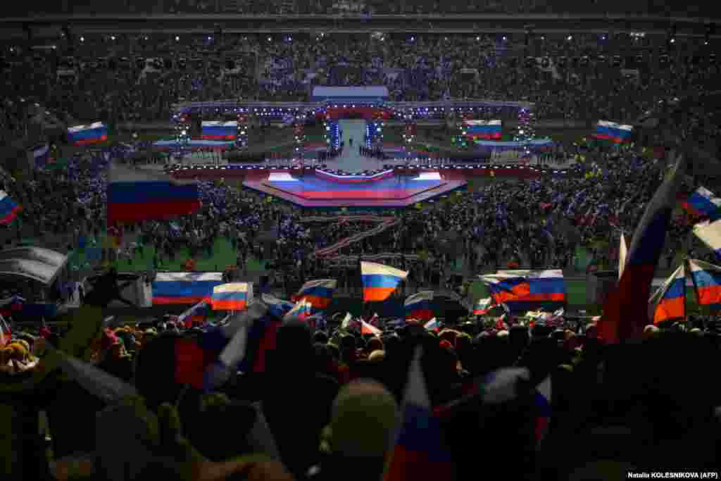 People wave Russian flags as President Vladimir Putin walks on stage to deliver his state-of-the-nation speech at Luzhniki Stadium in Moscow on February 22.