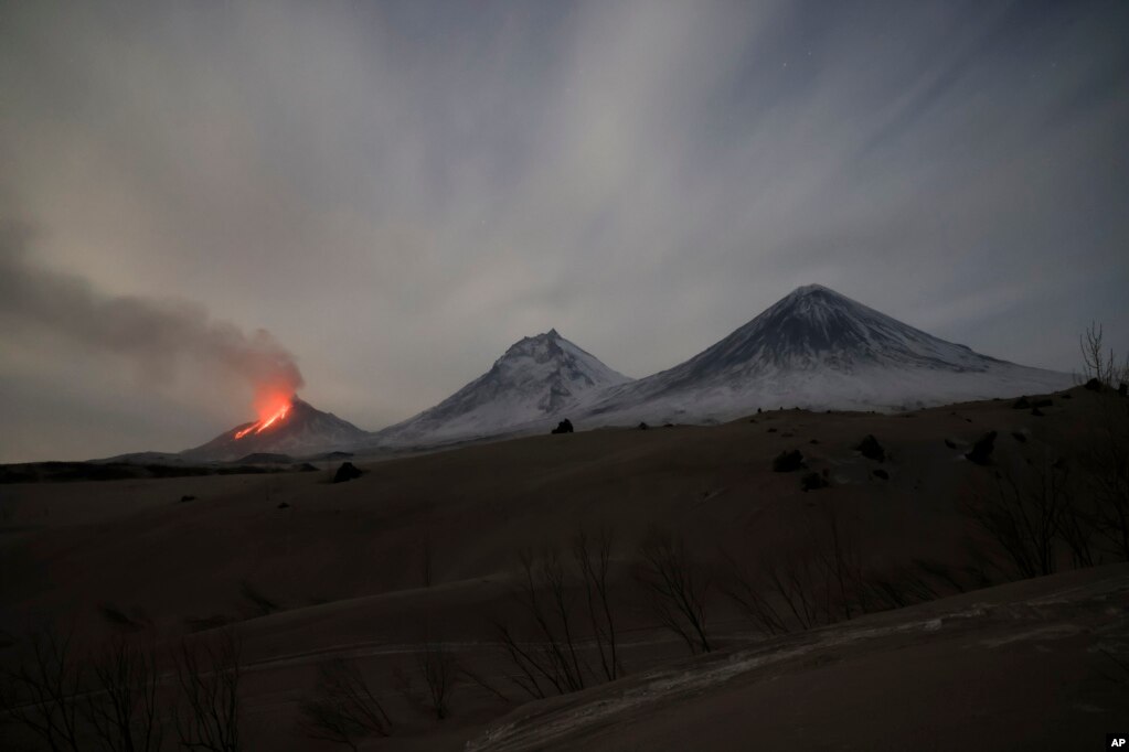 Llava dhe avulli janë të dukshme gjatë një shpërthimi të vullkanit Bezymianny (majtas) pranë vullkaneve Kamen (në qendër) dhe Klyuçevskaya Sopka në Gadishullin Kamçatka më 8 prill. Gadishulli Kamçatka, në Lindjen e Largët të Rusisë, shtrihet në jug të Oqeanit Paqësor të Veriut. Është një nga zonat më të përqendruara të aktivitetit gjeotermik në botë, me 160 vullkane në rajon, 29 prej të cilave besohet të jenë aktualisht aktive.