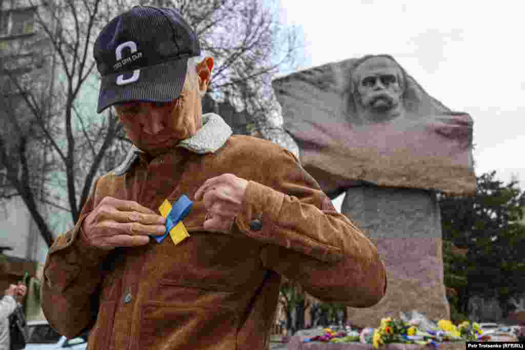 Активист Марат Турымбетов прикрепляет желто-голубую ленточку в память о погибших в Украине людях