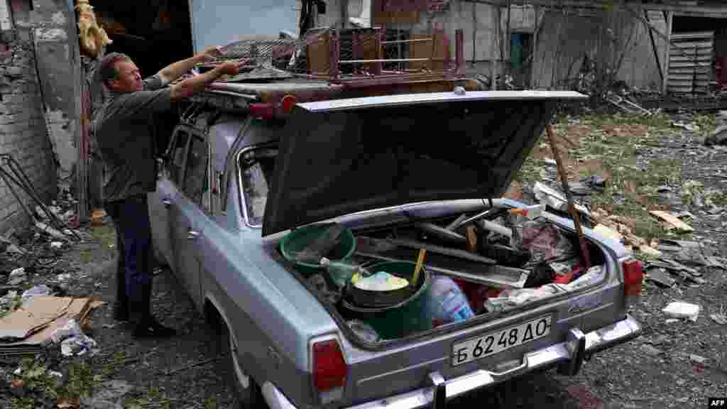 Egy helyi az autójába pakolja a holmiját a Kramatorszk városát érő éjszakai rakétatámadás után, 2023. július 9-én