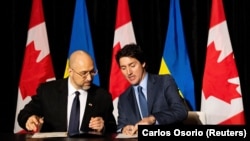 Ukrainian Prime Minister Denys Shmyhal (left) signs documents with his Canadian counterpart, Justin Trudeau, in Toronto, on April 11. 