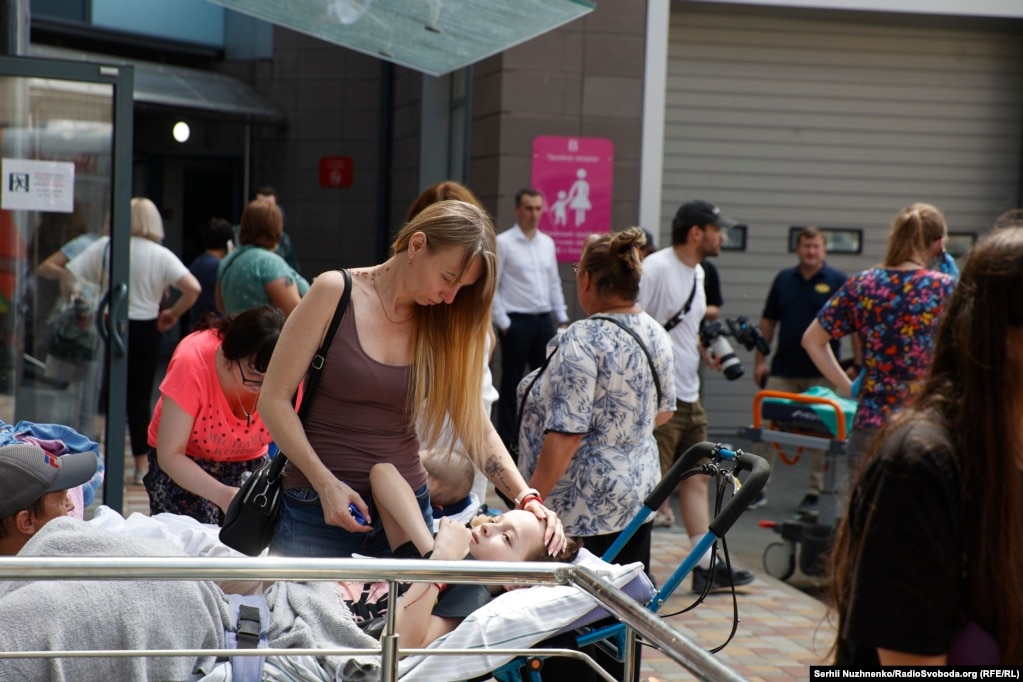 Жінка заспокоює дитину біля зруйнованої лікарні. Чимало дітей «Охматдиту» – це важкохворі пацієнти  