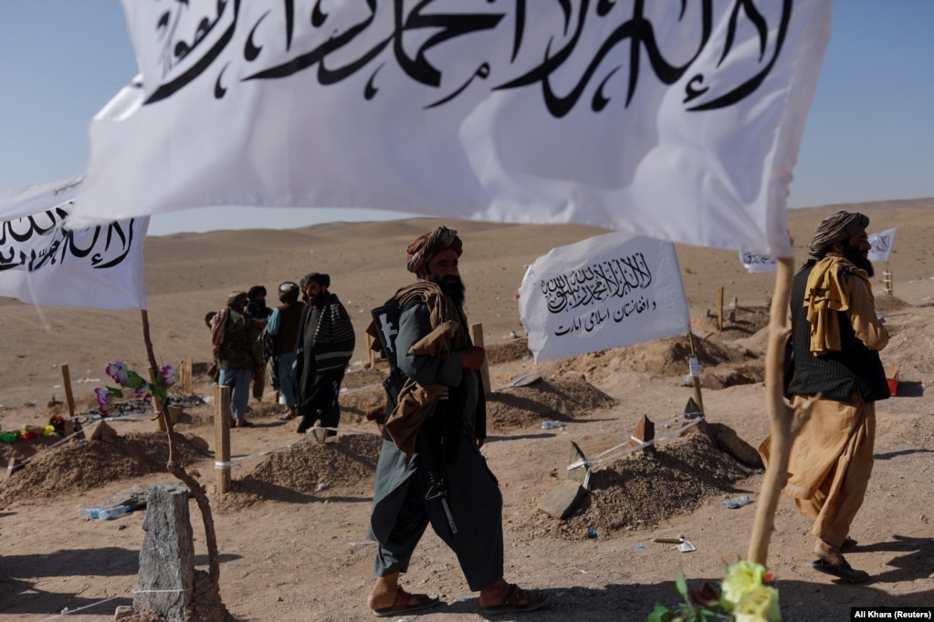 Soldati talebani attraversano un cimitero per le vittime del recente terremoto.   Il vicino Pakistan ha offerto assistenza, ma i funzionari di Islamabad hanno affermato che la consegna degli aiuti umanitari è sospesa dal 9 ottobre in attesa del "autorizzazione" per l'assistenza.  dai talebani.