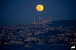 Hëna e plotë mbi minaret e xhamisë Camlica në Stamboll.