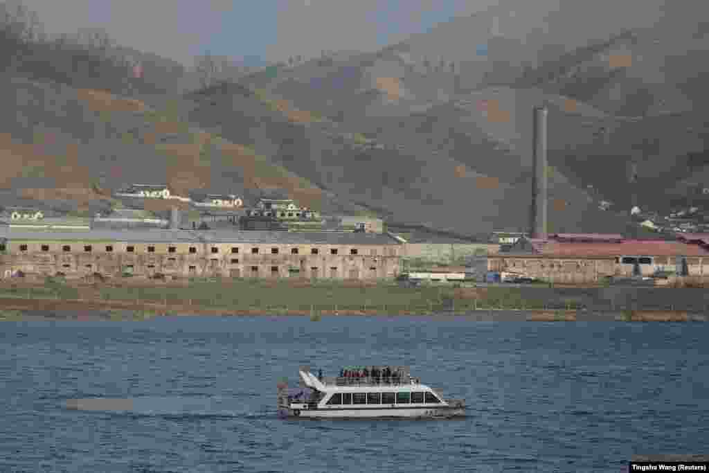 Një anije lundrimi kineze kalon pranë ndërtesave në Sinuiju të Koresë së Veriut në lumin Yalu, që ndan Korenë e Veriut dhe Kinën, në Dandong, provinca Liaoning, Kinë, 20 prill 2021.&nbsp;