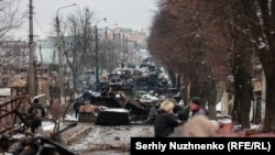 Мирные жители смотрят на уничтоженную российскую колонну в Буче. 1 марта 2022 года. Через два дня город заняли российские войска