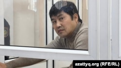 Аслан Утепов за стеклянной перегородкой для подсудимых в зале заседаний
