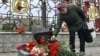 A woman lays flowers at a memorial near the train station in Kramatorsk in Ukraine's Donetsk region where dozens of civilians were killed by a Russian missile strike one year ago. 