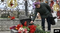 A woman lays flowers at a memorial near the train station in Kramatorsk in Ukraine's Donetsk region where dozens of civilians were killed by a Russian missile strike one year ago. 