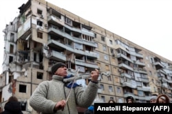 Чоловік грає на скрипці біля житлового будинку в Дніпрі, зруйнованого ракетним ударом 14 січня 2023 року