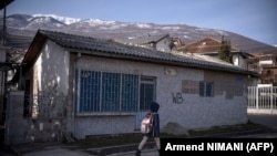 Devojčica prolazi pored napuštenog kafića u Peći na Kosovu, 9. februara 2023. Peć je bio bivša baza zloglasne srpske specijalne jedinice čiji su pripadnici, prema navodima grupa za ljudska prava, činili ratne zločine.
