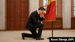 Moldovan Prime Minister Dorin Recean kneels in front of the national flag during a swearing-in ceremony in Chisinau on February 16.