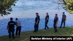 Serbian Police officers search a bank of the Drina River after a boat full of migrants capsized overnight on August 21-22. 