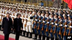 Emmanuel Macron francia elnök kínai vendéglátójával, Hszi Csin-ping kínai államfővel a díszőrség sorfala előtt Pekingben 2023. április 5-én