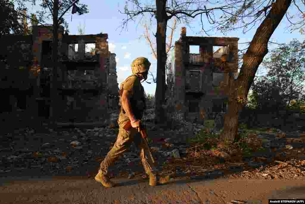 A Ukrainian soldier on patrol as he walks past an apartment building destroyed by an air strike in the town of Chasiv Yar.&nbsp;