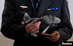 Švajcarski vazduhoplovac drži model vojnog helikoptera Eurocopter EC635.