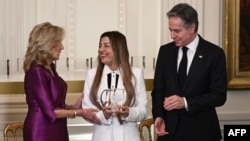 U.S. first lady Jill Biden (left) and Secretary of State Antony Blinken (right) present an International Women of Courage award to Benafsha Yaqoobi during an awards ceremony on March 4 at the White House in Washington.