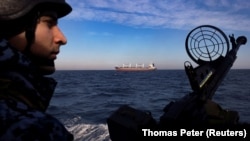 A soldier of Ukraine's coast guard mans a gun on a patrol boat as a cargo ship passes by in the Black Sea on February 7.