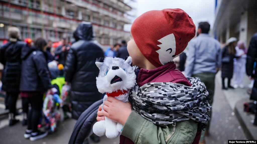 Një fëmijë shikon teksa vullnetarë lëshohen me litarë në Klinikën e Pediatrisë, pasi iu dhurua një lodër.