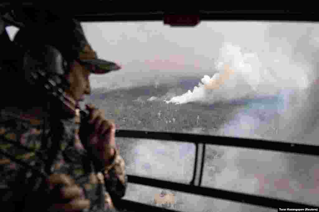 A specialist looks out of a helicopter during an operation to contain wildfires in Kazakhstan&#39;s eastern Abai region.