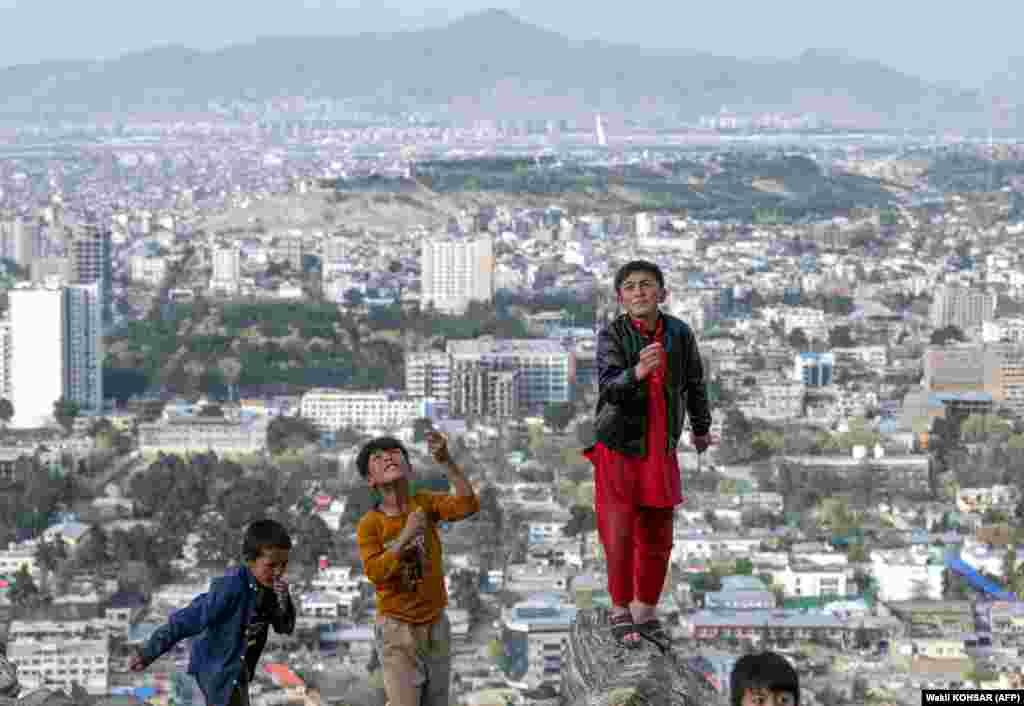 Afghan boys fly kites on a hilltop in Kabul.