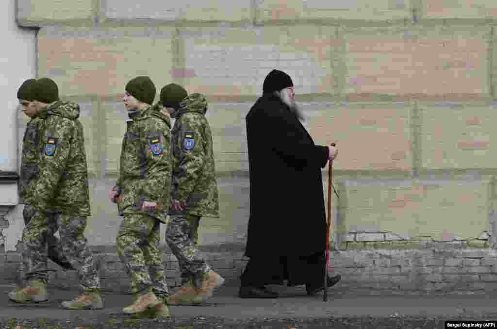 This March 14 photo shows Ukrainian soldiers passing a monk in the Kyiv Pechersk Lavra as tensions mount over a March 29 deadline for clerics to leave the property. The clergy have declared they will stay on in their historic home, as their supporters vow to back them&nbsp;&ldquo;whatever the cost.&rdquo; &nbsp;