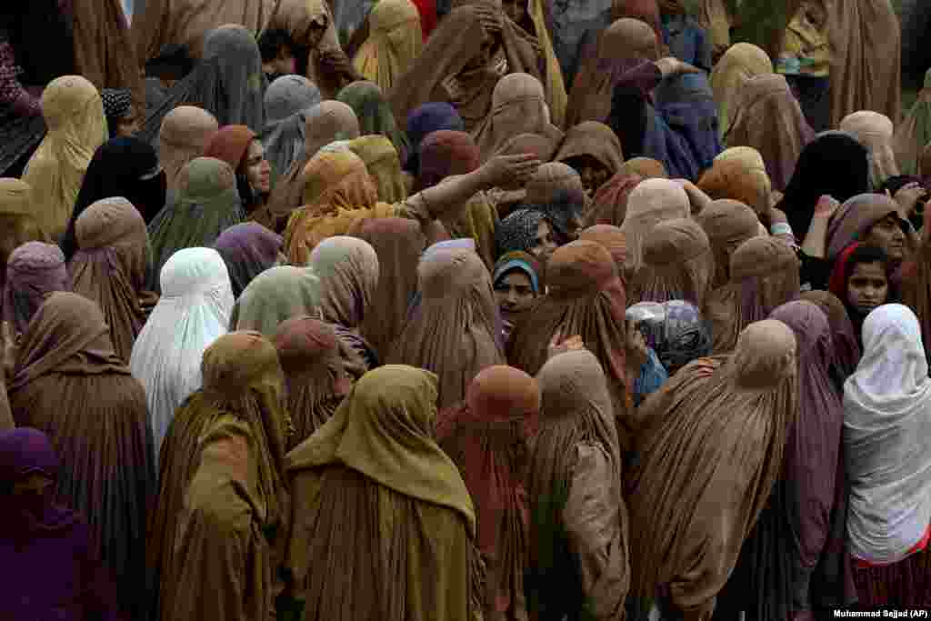 Women gather to wait their turn to get a free sack of wheat flour at a distribution point in Peshawar, Pakistan.