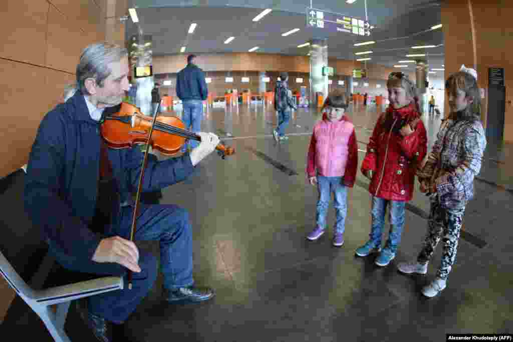 Copii ascultând un muzician care exersează în interiorul aeroportului, în martie 2014. La deschiderea aeroportului în mai 2012, viceprim-ministrul Ucrainei a prezis că noua structură elegantă va deservi aproximativ 4 milioane de pasageri pe an, deja în 2015.