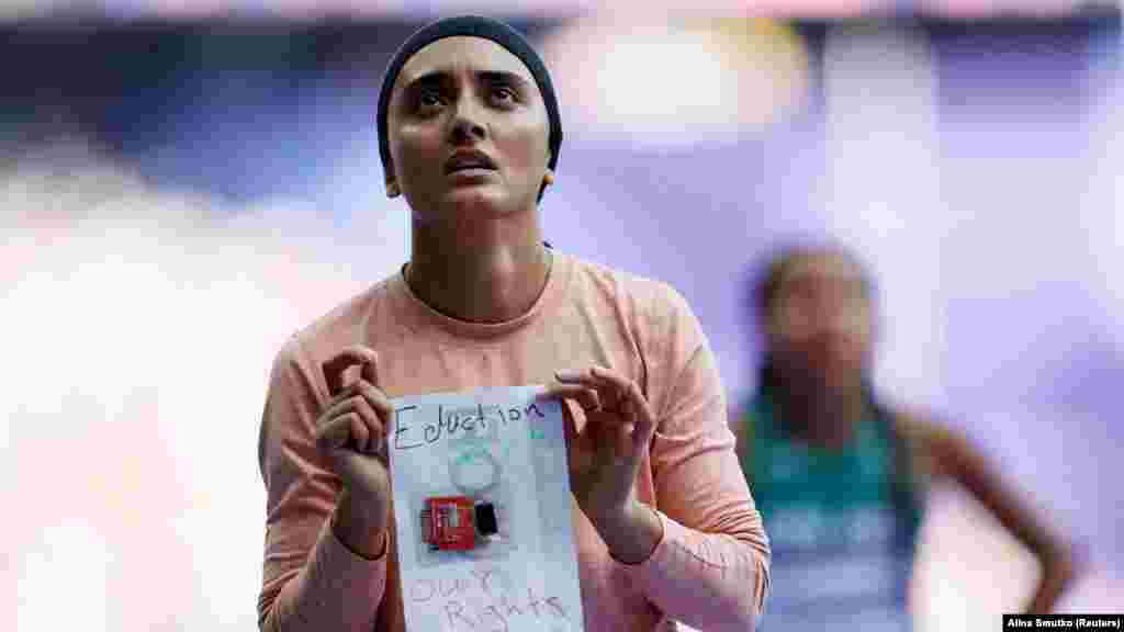 Afghan sprinter Kimia Yosufi shows a handwritten slogan that reads &quot;Education, sports, our rights&quot; after reaching the finish line of the 100-meter track preliminary heat on August 2. The Taliban government, which has denied women education and sports since returning to power in August 2021, has said that it does not recognize the participation of female members of Afghanistan&rsquo;s Olympic team in the Paris games.