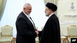 Iranian President Ebrahim Raisi (right) greets the leader of the Palestinian militant group Hamas, Ismail Haniyeh, in Tehran on June 2o.