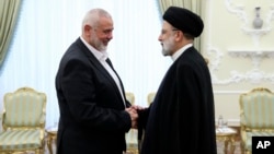 In this photo released by the Iranian president's office, President Ebrahim Raisi (right) greets the leader of the Palestinian militant group Hamas, Ismail Haniyeh, in Tehran on June 20.