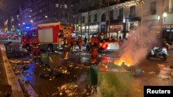 Vatrogasci u Parizu gase vreće smeća koje su zapalili demonstranti, nezadovoljni ishodom drugog glasanja o nepovjerenju u Donjem domu parlamenta, 20. mart 2023.