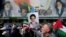 Iranians walk past a mural showing the late revolutionary founder Ayatollah Khomeini (right) Supreme Leader Ayatollah Ali Khamenei (left) and Basij paramilitary forces as they hold posters of Khomeini and Iranian and Palestinian flags in an anti-Israeli gathering after Friday Prayers in Tehran on April 19.