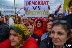 Un susținător ridică un panou pe care scrie „Democrat vs Dictator” în timpul unui miting în sprijinul președintelui Partidului Popular Republican (CHP) și a candidatului la președinție, Kemal Kilicdaroglu, la Kocaeli, pe 28 aprilie 2023.