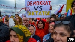 O susținătoare a lui Kemal Kilicdaroglu, candidatul la președinție al Partidului Republican al Poporului (CHP), ține o pancartă pe care scrie „Democrat vs Dictator”, în timpul unui miting de susținere, în Kocaeli, Turcia, 28 aprilie 2023.