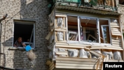 Žena čisti ruševine iz stana u višespratnoj stambenoj zgradi oštećenoj u granatiranju u Lugansku, Ukrajina pod ruskom kontrolom, 7. juna, 2024. 