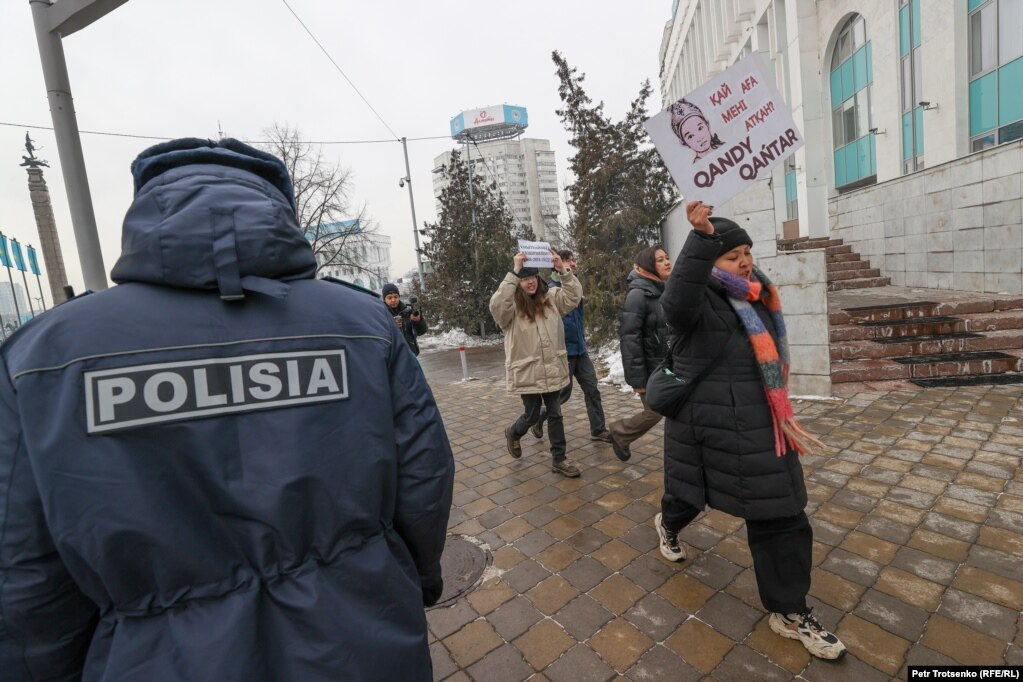 Активисты движения Oyan, Qazaqstan проходят мимо сотрудника полиции