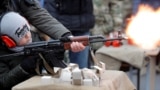 An officer of Belarus's Interior Ministry teaches a child to fire an automatic weapons in March 2020